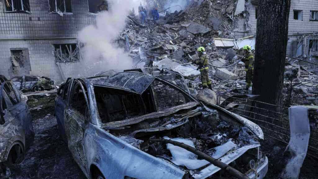 Rettungskräfte löschen ein Feuer an einem Auto vor einem mehrstöckigen Wohnhaus, das durch einen russischen Angriff in der ukrainischen Hauptstadt zerstört wurde. Foto: Evgeniy Maloletka/AP/dpa