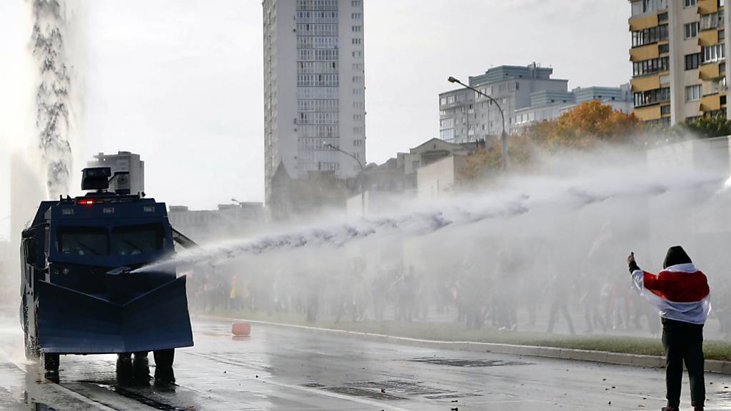 dpatopbilder - Polizisten setzten einen Wasserwerfer gegen Demonstranten ein. Trotz eines Großaufgebots an Sicherheitskräften haben Zehntausende Menschen gegen den autoritären Staatschef Lukaschenko demonstriert. Foto: Uncredited/AP/dpa