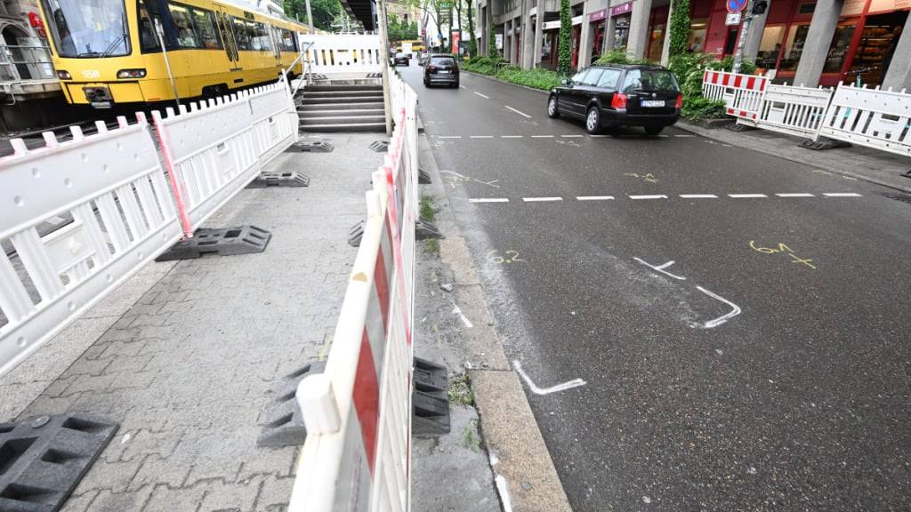 Kreidezeichen sind auf der Straße an einer Unfallstelle in Stuttgart angebracht und Absperrgitter sind aufgestellet. Foto: Bernd Weißbrod/dpa