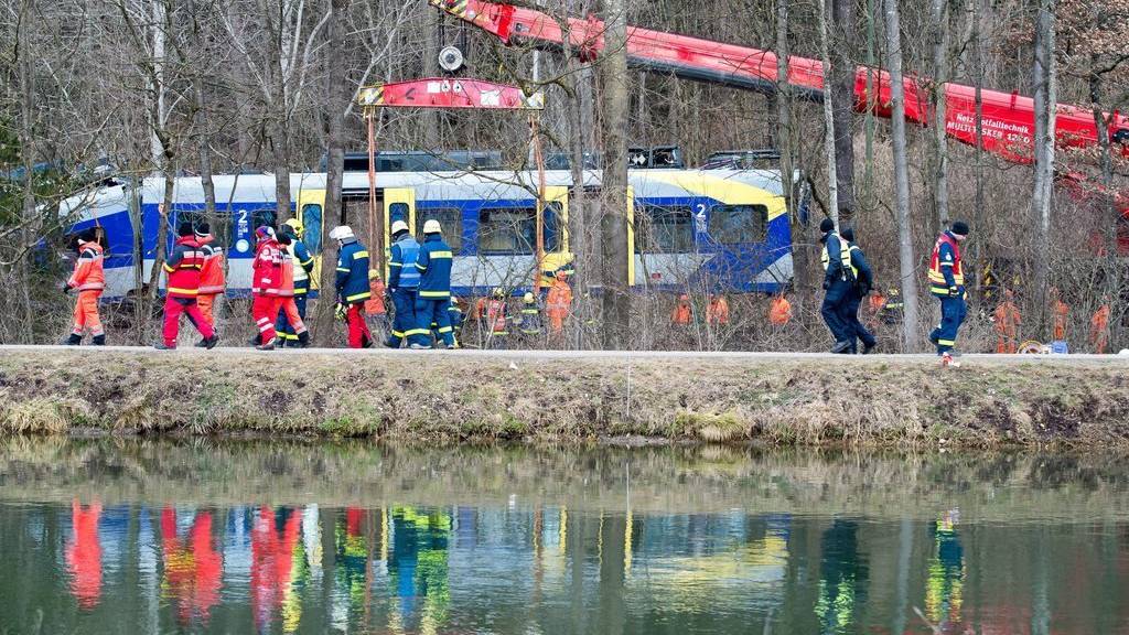 epa05154295 Task force units watch a crane lift a train car at the site of the train accident in Bad Aibling, Germany, 11 February 2016. Two Meridian commuter trains of the private railway company Bayerische Oberlandbahn collided head-on at high speed near Bad Aibling on the single-track line between Holzkirchen and Rosenheim. At least 10 people were killed and 80 injured in the accident as the two trains carrying a total of 150 people impacted on 09 February 2016.  EPA/PETER KNEFFEL