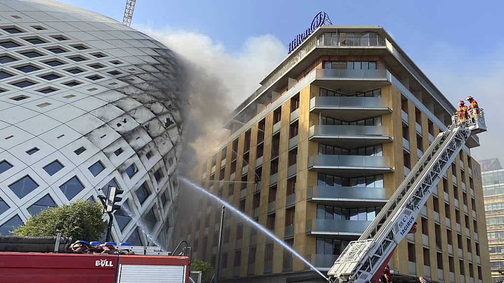 Feuerwehrleute löschen einen Brand im Geschäftsviertel der libanesischen Hauptstadt. Betroffen ist das sich noch im Bau befindlichen Gebäude (links), das von der Architektin Zaha Hadid entworfen wurde.