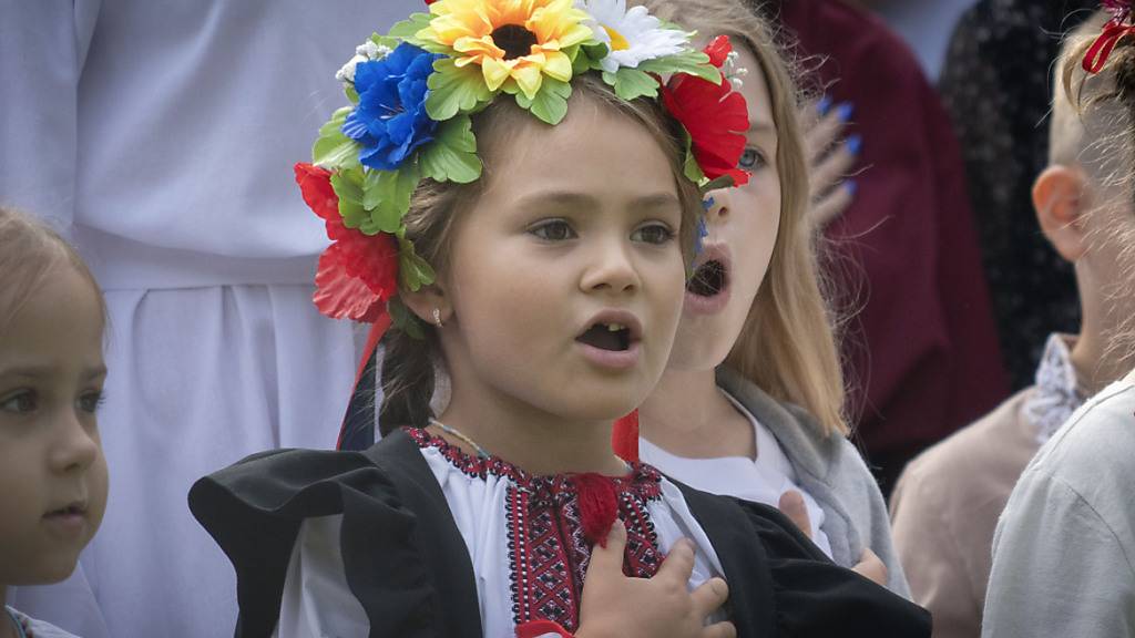 Schulkinder singen die ukrainische Nationalhymne, während sie an einer Zeremonie zum ersten Schultag teilnehmen. In der Ukraine wird der 1. September traditionell als Tag des Wissens begangen, an dem das neue Schuljahr beginnt. Foto: Efrem Lukatsky/AP/dpa