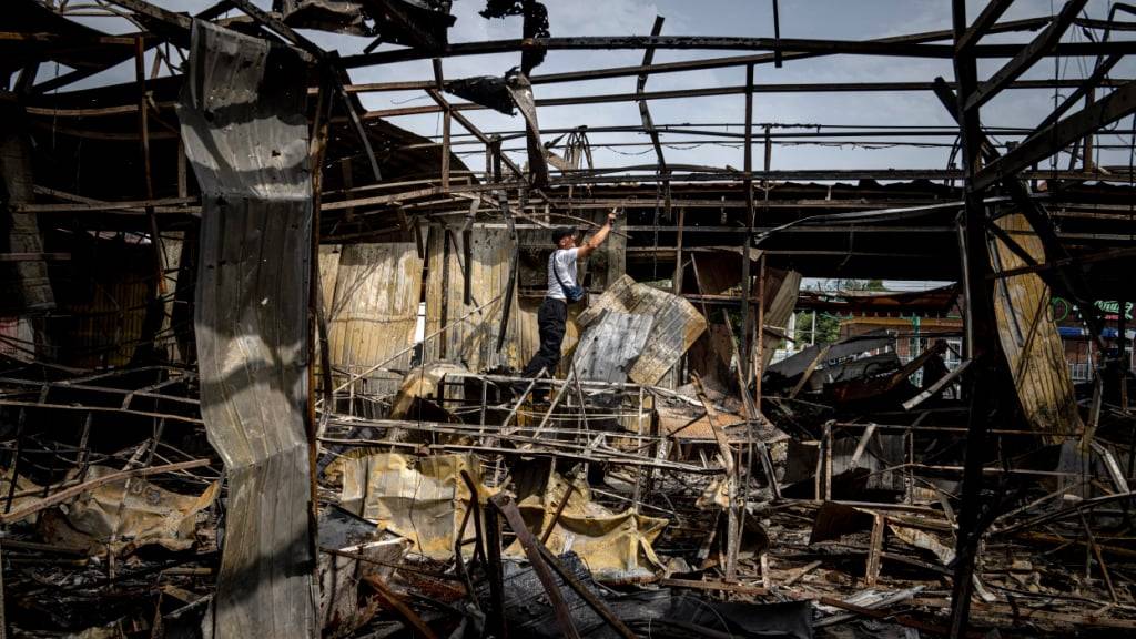 ARCHIV - Ein Mann sammelt Kupferdrähte auf einem Markt in Nikopol, der durch russischen Beschuss zerstört wurde. Foto: Evgeniy Maloletka/AP/dpa/Symbolbild