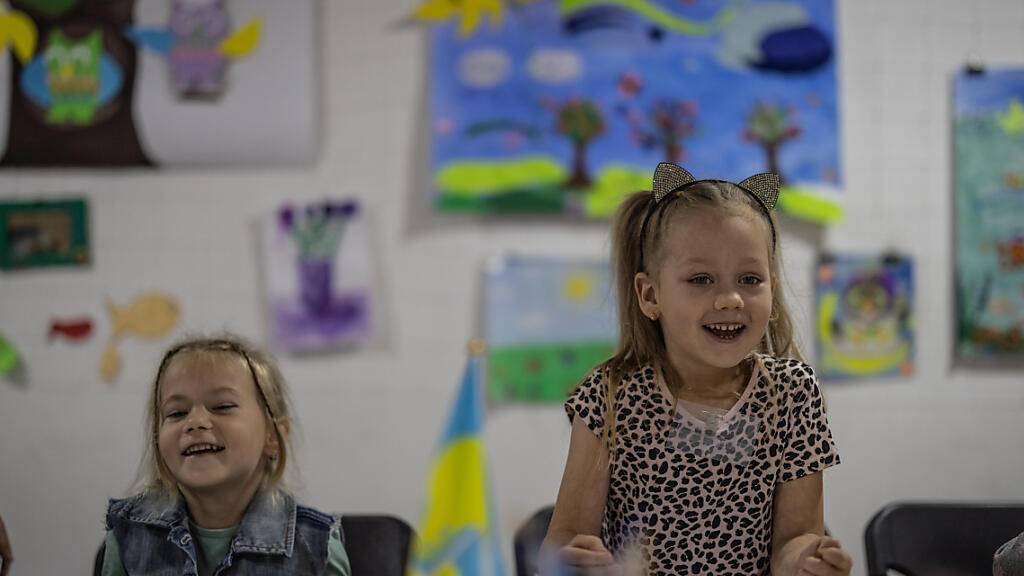 Die fünfjährige Dasha (r) lacht beim Unterricht im «Tato Hub» in Kramatorsk, einer Einrichtung von Freiwilligen für im Kriegsgebiet gebliebene Kinder. Viele Kinder kommen aus Ortschaften, die Brennpunkte des Krieges sind. Foto: Oliver Weiken/dpa