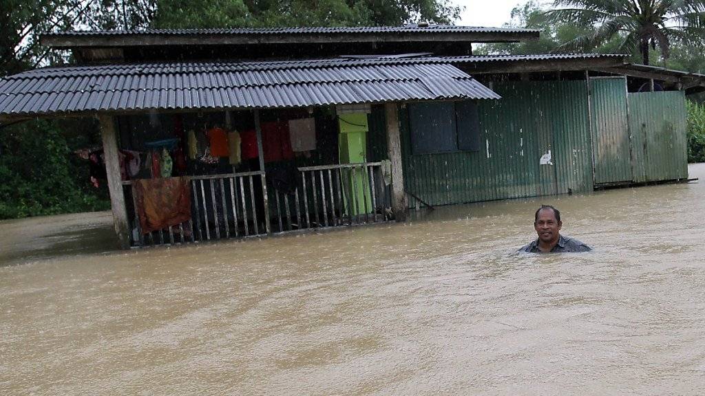 Ein Mann watet durch die Fluten im Süden Thailands. (Archiv)
