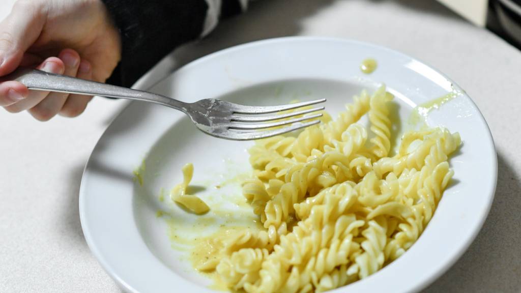 ARCHIV - Ein Kind isst Nudeln von einem Teller. Was Menschen essen, hat auch damit zu tun, was sie sich leisten können. Foto: Jens Kalaene/dpa-Zentralbild/dpa