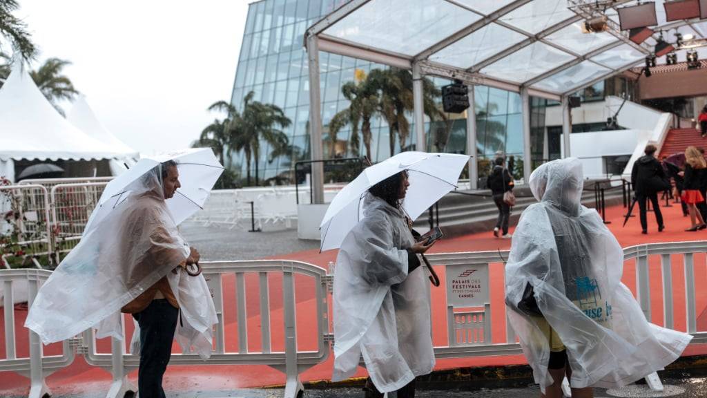 Menschen mit Regenschutz in Cannes. Foto: Lewis Joly/Invision/AP/dpa