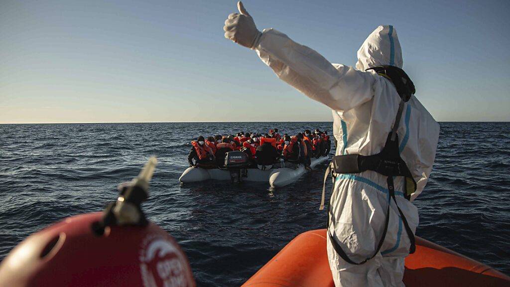 ARCHIV - Ein Mitarbeiter NGO «Open Arms» vor der libyschen Küste gestikuliert in Richtung eines überfüllten Schlauchbootes, auf dem sich Migranten aus verschiedenen afrikanischen Ländern befinden (Bild vom 06.02.). Hilfsorganisationen fahren immer wieder  aufs Meer, um Menschen vor dem Ertrinken zu retten. Foto: Pablo Tosco/AP/dpa