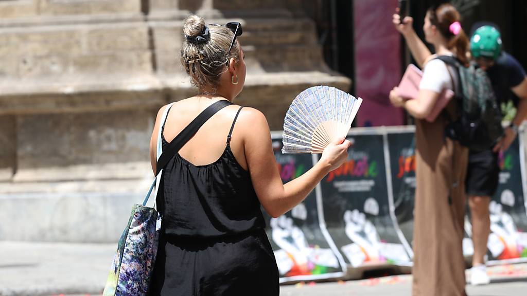 Um die Temperaturen irgendwie aushalten zu können, greifen viele auf Hilfsmittel wie Fächer zurück. Foto: Alberto Lo Bianco/LaPresse via ZUMA Press/dpa