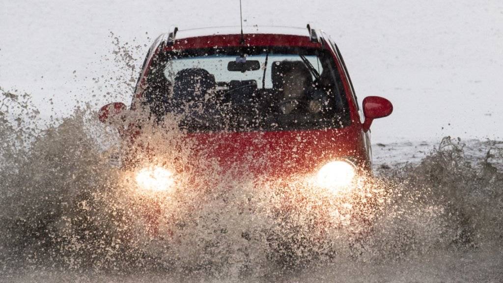 Eine Autofahrerin auf einer überfluteten Strasse. Frauen sind gemäss einem Unfallexperten generell vorsichtiger unterwegs und scheuen das Risiko. (Archivbild)