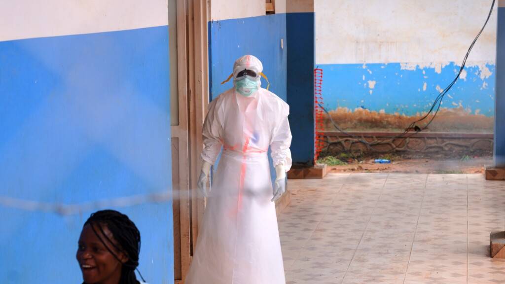 ARCHIV - Ein Mitarbeiter des Gesundheitswesens steht vor einem Ebola-Behandlungszentrum im Kongo. Foto: Dirole Lotsima Dieudonne/AP/dpa/Archivbild