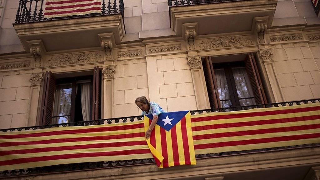 Eine Frau hängt die katalanische Flagge an ihren Balkon - das spanische Verfassungsgericht hat das Abspaltungsbegehren der Region Katalonien nun für illegal erklärt. (Archiv)