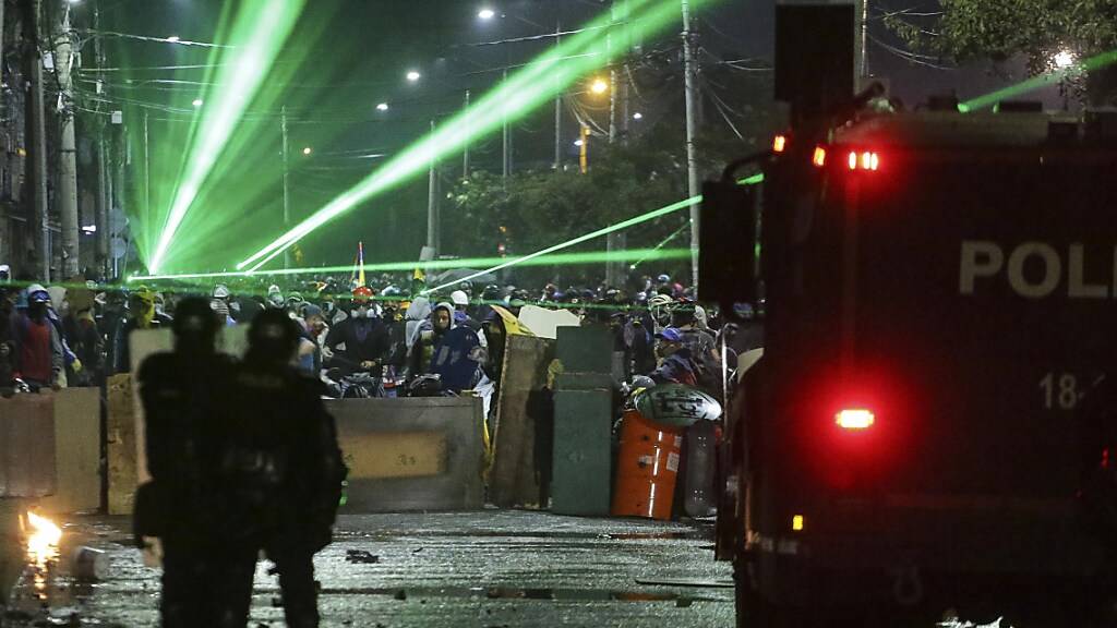 Anti-Regierungs-Demonstranten zielen während eines Protests mit Lasern auf Polizisten. Foto: Ivan Valencia/AP/dpa