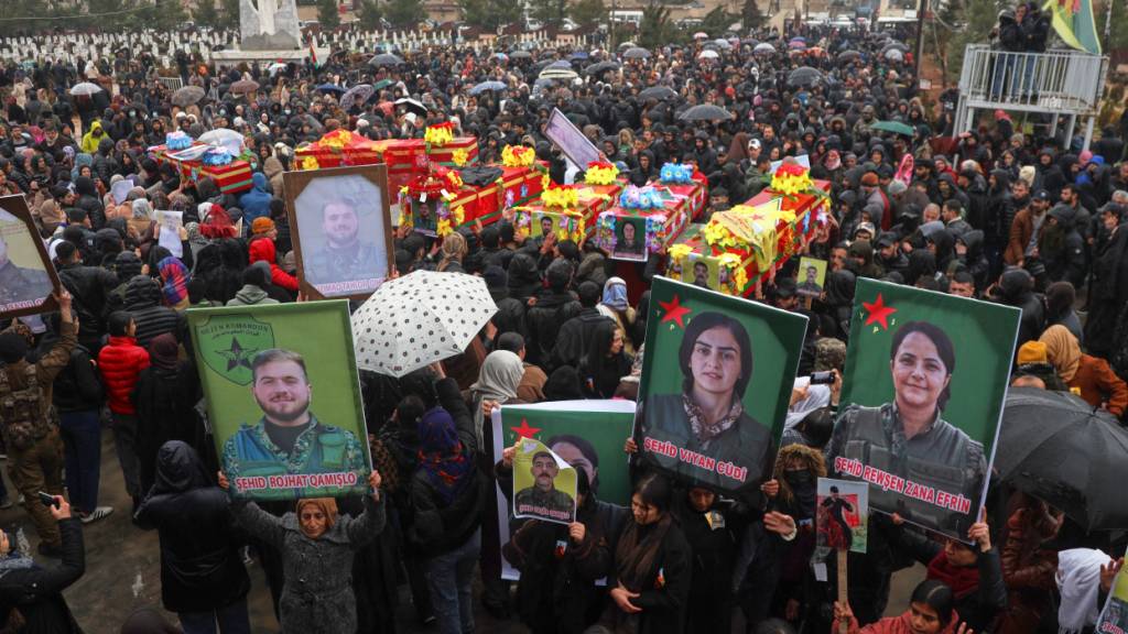 Trauernde nehmen an der Beerdigung von Kämpfern der kurdisch geführten Syrischen Demokratischen Kräfte (SDF) teil, die Anfang dieses Monats bei Zusammenstößen mit syrischen Regierungstruppen getötet wurden. Foto: Baderkhan Ahmad/AP/dpa