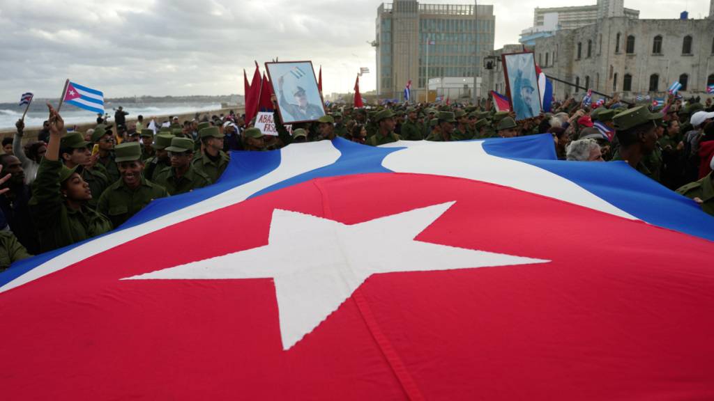 Menschen tragen eine kubanische Flagge während einer von der Regierung organisierten Kundgebung in Havanna. Foto: Ramon Espinosa/AP/dpa