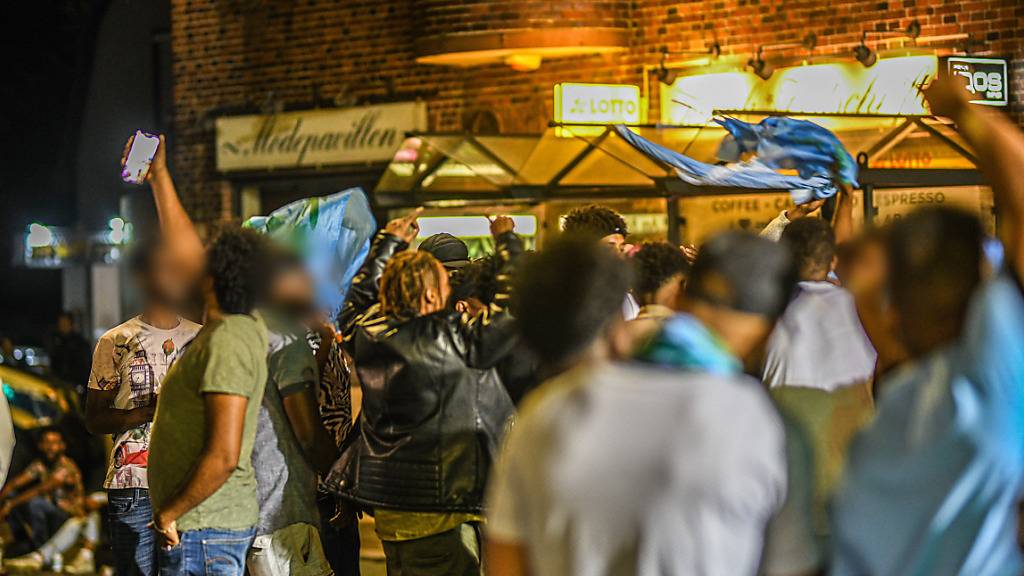 Eine Gruppe von Menschen feiert während sie nach Ausschreitungen bei einer Eritrea-Veranstaltung von Polizeikräften eingekesselt ist. Foto: Jason Tschepljakow/dpa - ACHTUNG: Person(en) wurde(n) aus rechtlichen Gründen gepixelt