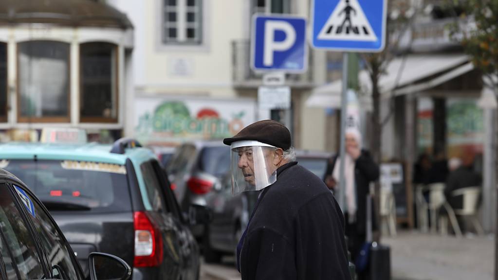 Ein alter Mann mit einem Gesichtsschutz überquert eine Straße. Auch in Portugal ist erstmals die neue Coronavirus-Variante Omikron festgestellt worden. Foto: Ana Brigida/AP/dpa