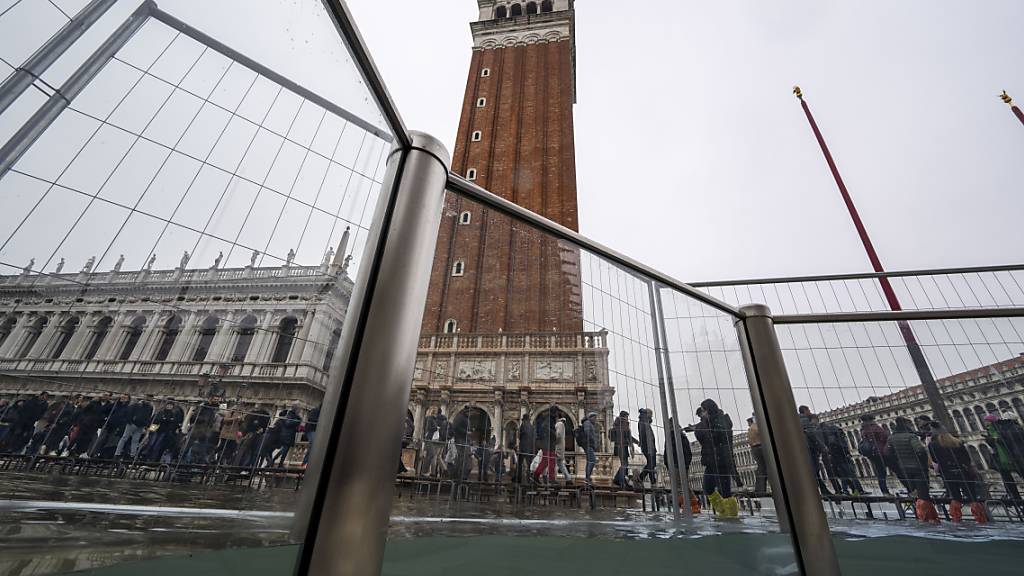 ARCHIV - Der überschwemmte Markusplatz: Kürzlich installierte Glasbarrieren verhindern eine größere Flut. Foto: Domenico Stinellis/AP/dpa