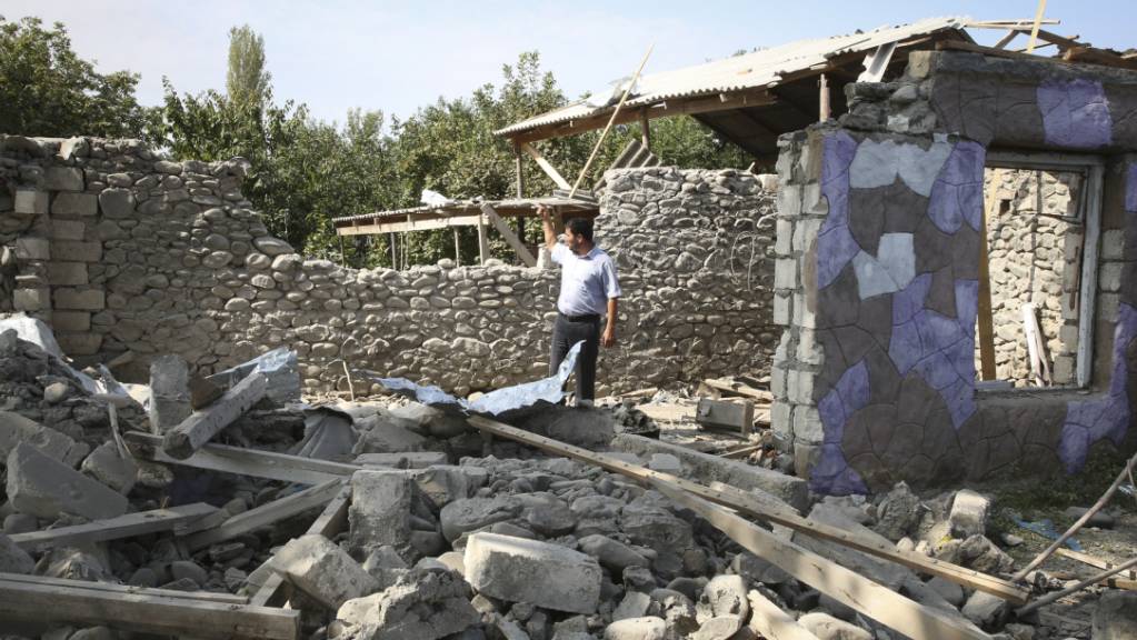 Ein Mann steht in den Ruinen eines Hauses, das angeblich während der Kämpfe beschädigt wurde. Foto: Aziz Karimov/AP/dpa
