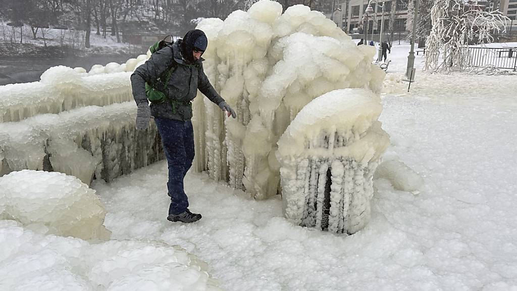 Ein Mann geht über gefrorenes Eis. Foto: Ted Shaffrey/AP/dpa