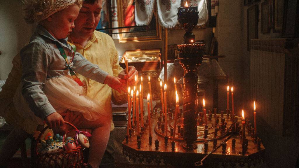 Ein Vater hilft seiner Tochter beim Anzünden einer Kerze während der orthodoxen Osterfeier in der St. Johannes Theologen Kirche der Orthodoxen Kirche der Ukraine in Charkiw. Am Wochenende sollen es in der Ukraine eine Waffenruhe geben, damit die Menschen Ostern feiern können. Foto: George Ivanchenko/AP/dpa