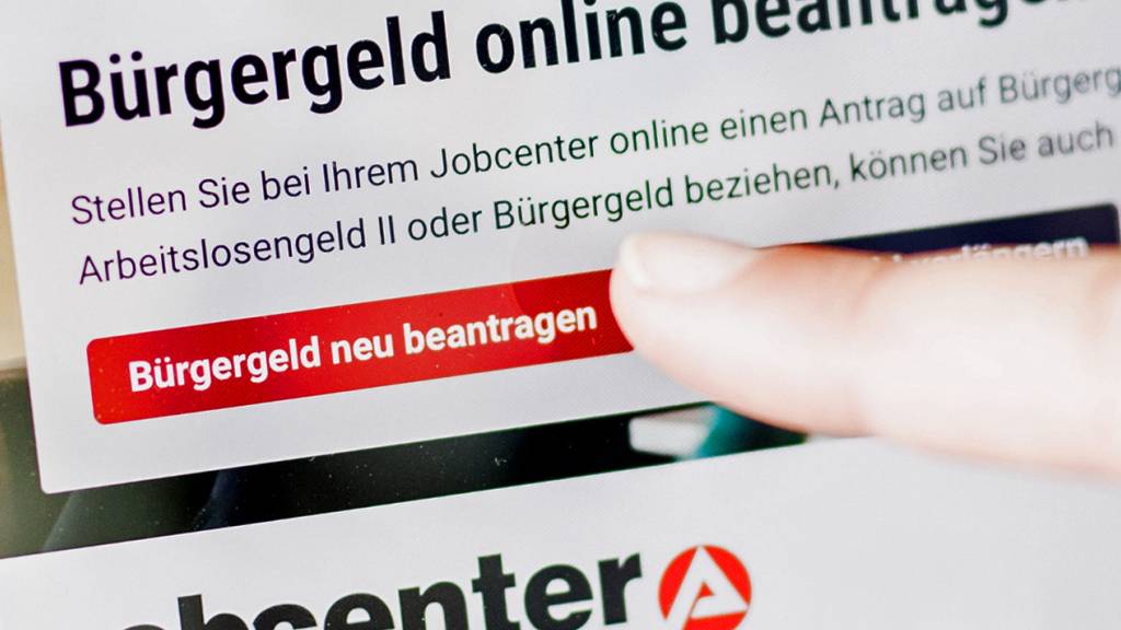ARCHIV - Eine Frau tippt auf einem Tablet auf einen Link zum Beantragen des Bürgergeldes im Kundenbereich im Jobcenter Berlin-Mitte. Foto: Carsten Koall/dpa