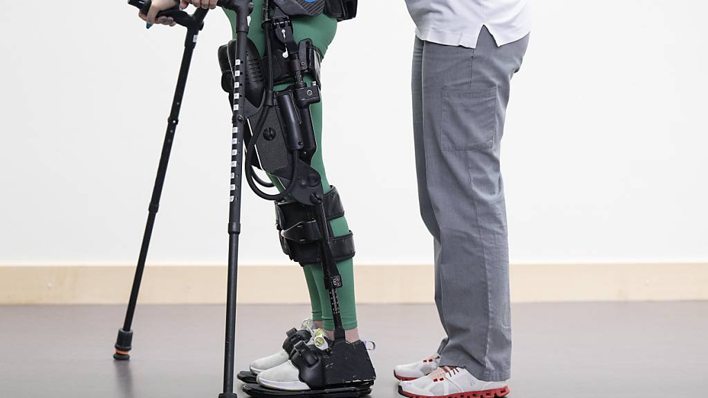 Ein Patientin des Schweizer Paraplegiker-Zentrums in Nottwil geht mit dem Exoskelett und einer Therapeutin durch den Gang. (Archivbild)