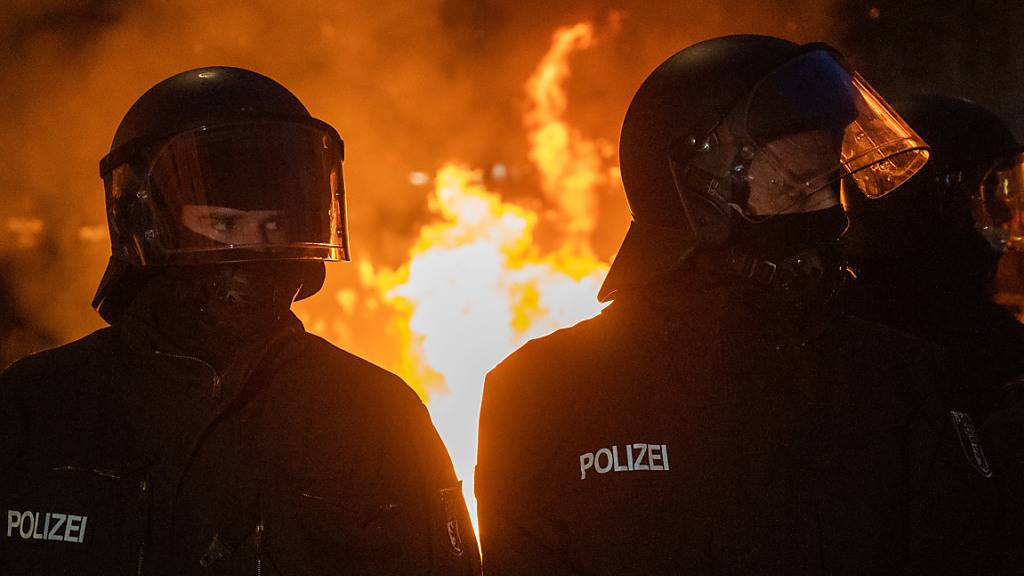 Polizisten stehen vor einem Feuer am Rande des Demonstrationszug linker und linksradikaler Gruppen unter dem Motto «Demonstration zum revolutionären 1. Mai». Foto: Christophe Gateau/dpa