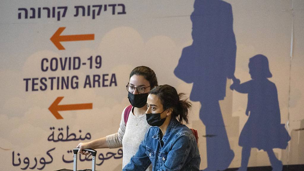 Reisende sind am Ben-Gurion-Flughafen in Tel Aviv unterwegs. Um die Verbreitung der neuen Omikron-Variante des Coronavirus einzudämmen, führt Israel die umstrittene Handy-Überwachung von Corona-Patienten und deren Kontakten wieder ein. Foto: Ariel Schalit/AP/dpa