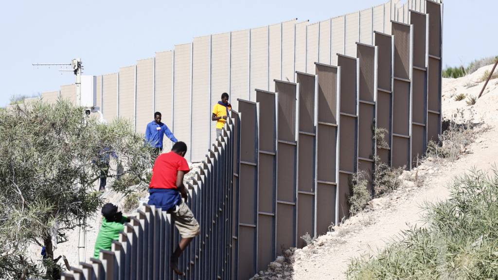 ARCHIV - Migranten klettern über einen Zaun auf der Insel Lampedusa. Foto: Cecilia Fabiano/LaPresse via ZUMA Press/dpa