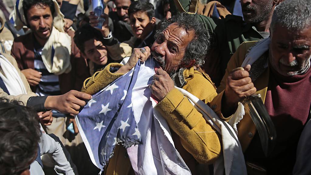 Ein Anhänger der jemenitischen Huthi-Bewegung zerreißt während eines Protest vor der geschlossenen US-Botschaft eine US-Fahne, nachdem US-Außenminister Pompeo angekündigt hat, die Huthi-Rebellen als Terrororganisation einzustufen. Foto: Hani Mohammed/AP/dpa