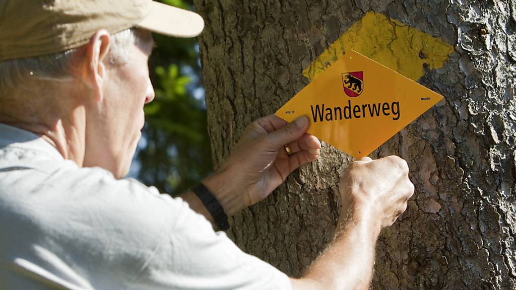 Ein Freiwilliger bringt ein Wanderwegsignal an. Die Berner Wanderwege sind zusammen mit der Bildungswerkstatt Bergwald die Träger des diesjährigen Preises der Berner Burgergemeinde. (Archivbild)