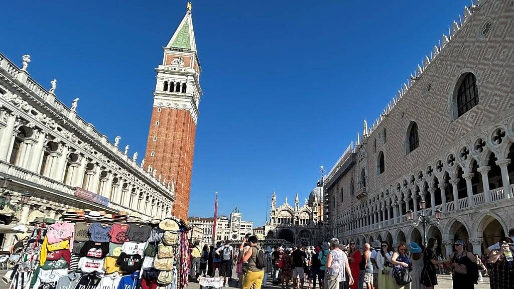 ARCHIV - Touristen stehen auf dem Markusplatz mit Campanile (M) und Dogenpalast (r). Foto: Christoph Sator/dpa