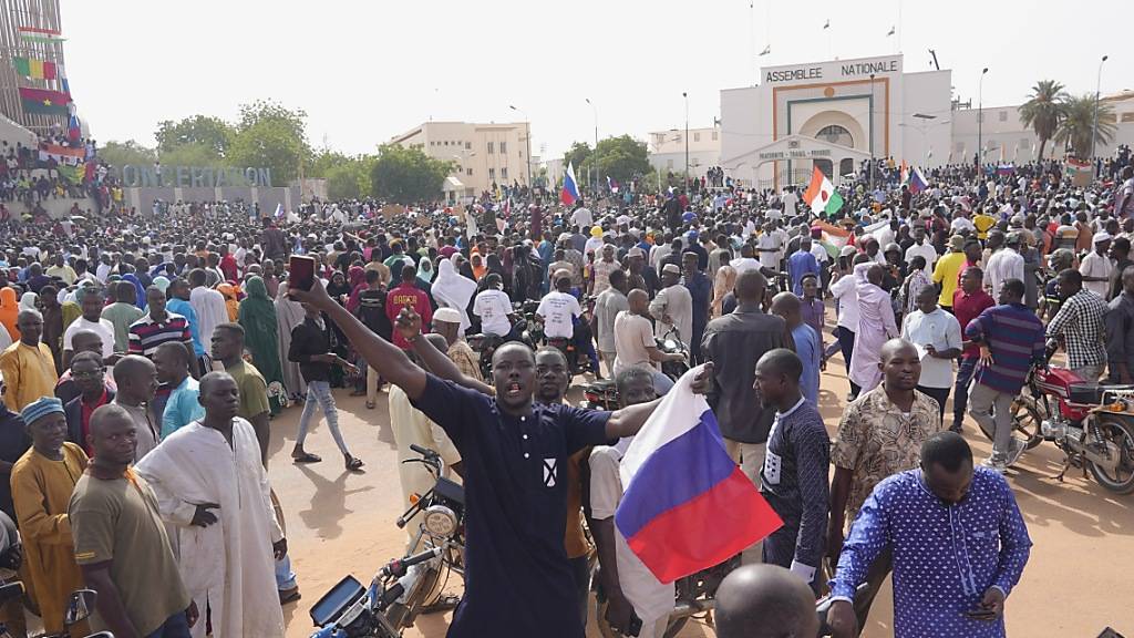 Ein Teilnehmer des Marsches in Niamey im Niger, zu dem Anhänger des Putschisten General Omar Tchiani aufgerufen haben, hält eine russische Flage in der Hand. Foto: Sam Mednick/AP/dpa
