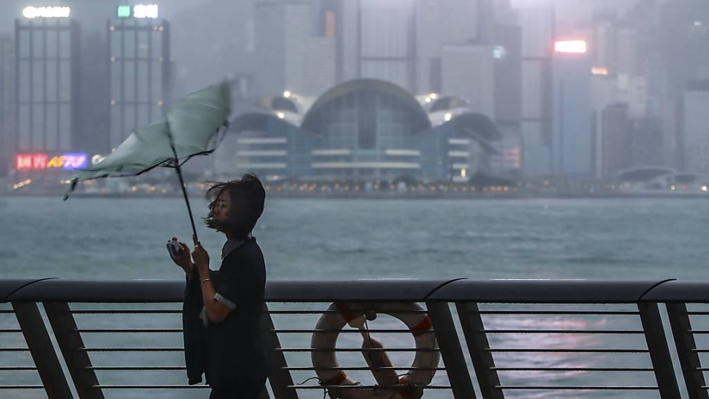 dpatopbilder - Der Regenschirm einer Frau wird weggeweht, als Taifun «Saola» mit starkem Wind und Regen auf Hongkong trifft. Foto: Daniel Ceng/AP/dpa