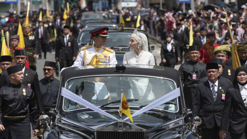 HANDOUT - Bruneis Prinz Abdul Mateen und Braut Anisha Rosnah in ihrem Auto während der Hochzeitsprozession. Foto: Brunei's Information Department/AP/dpa - ACHTUNG: Nur zur redaktionellen Verwendung und nur mit vollständiger Nennung des vorstehenden Credits