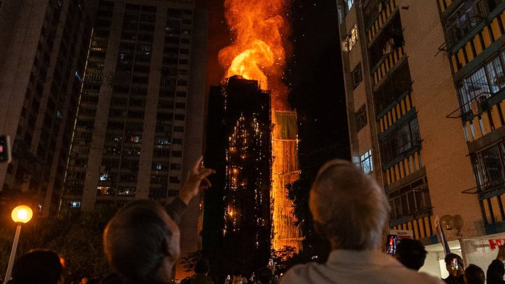 dpatopbilder - Menschen betrachten die Flammen, die ein Gebäude verschlingen, nachdem im Wang Fuk Court, einer Wohnsiedlung im Stadtteil Tai Po in den New Territories von Hongkong, ein Feuer ausgebrochen ist. Foto: Chan Long Hei/AP/dpa