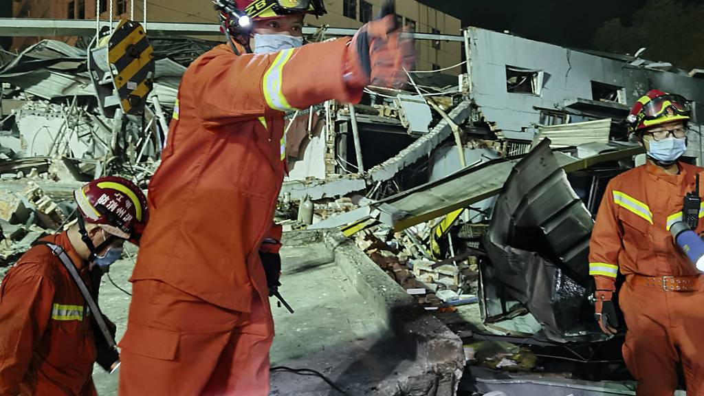 Feuerwehrleute arbeiten zwischen eingestürzten Gebäuden nach der Explosion eines Tanklastwagens. Foto: Uncredited/CHINATOPIX/AP/dpa