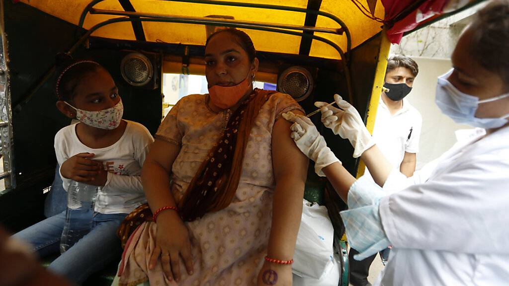 Eine Mitarbeiterin des Gesundheitswesens impft in Ahmedabad eine Frau gegen das Coronavirus. Foto: Ajit Solanki/AP/dpa