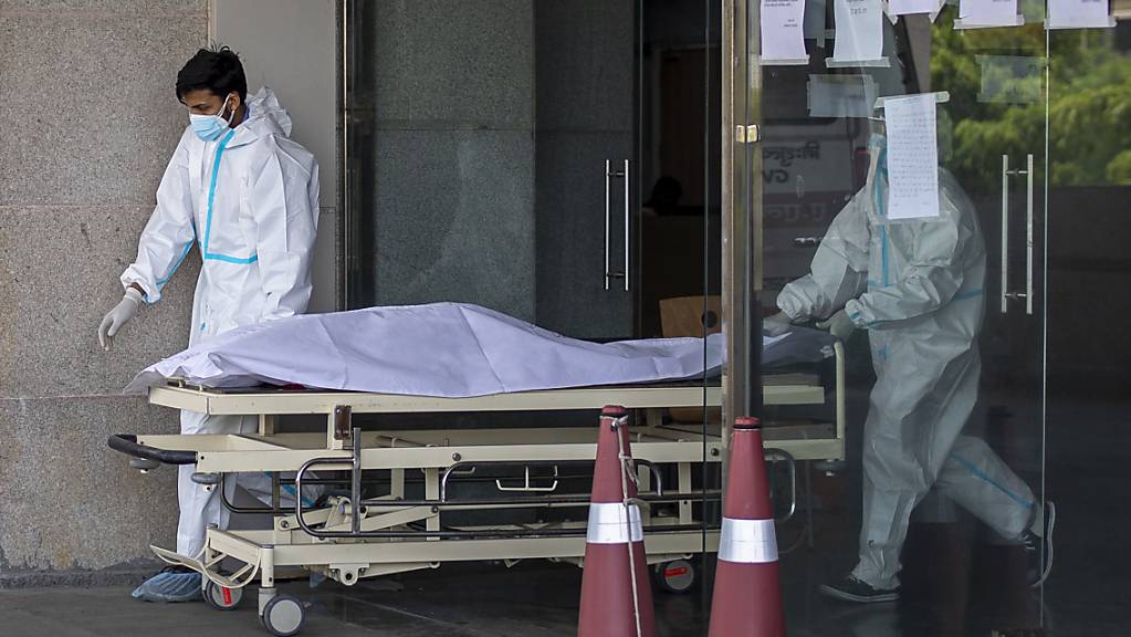 Medizinische Mitarbeiter in Schutzausrüstung transportieren den Leichnam eines Corona-Toten auf einer Trage aus einem Krankenhaus für Corona-Patienten. Foto: Altaf Qadri/AP/dpa