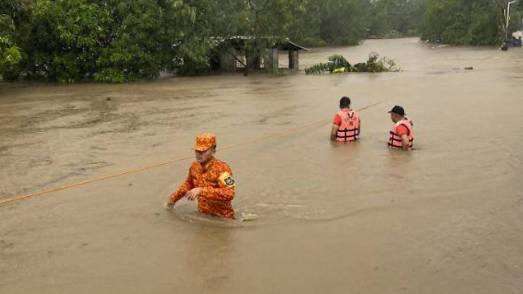 HANDOUT - Rettungskräfte waten durch die vom Taifun Doksuri verursachten Überschwemmungen. Foto: Philippine Coast Guard/AP/dpa - ACHTUNG: Nur zur redaktionellen Verwendung und nur mit vollständiger Nennung des vorstehenden Credits