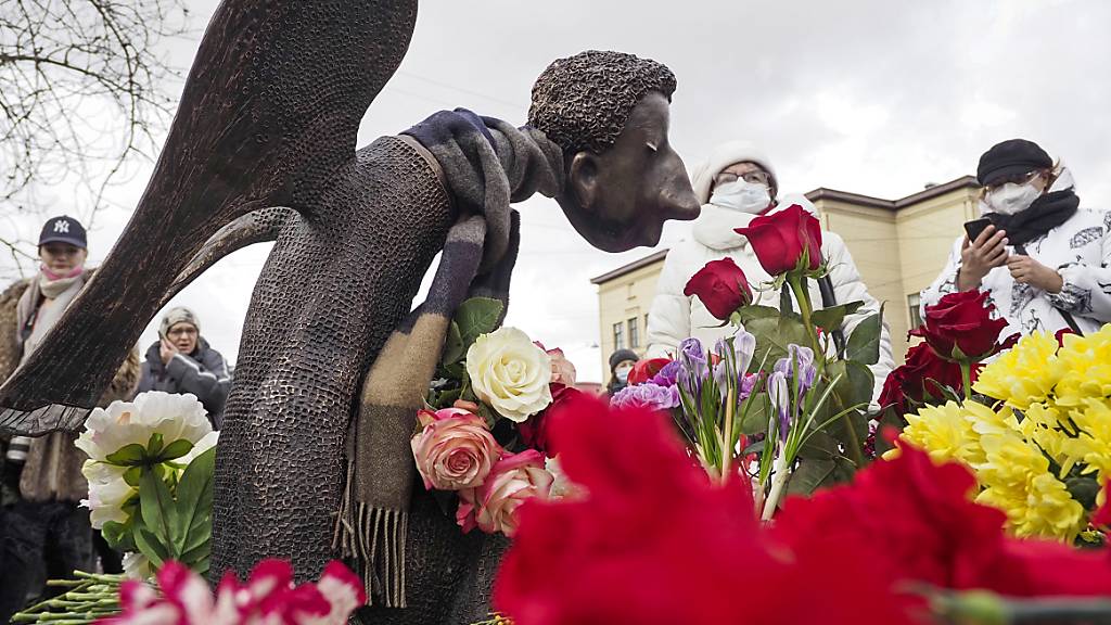 ARCHIV - Menschen stehen vor der mit Blumen umringten Skulptur «Trauriger Engel» des Bildhauers Shustrov, während der Eröffnung einer Gedenkstätte für medizinische Mitarbeiter, die in St. Petersburg an einer Corona-Infektion gestorben sind (Archivbild). Foto: Dmitri Lovetsky/AP/dpa
