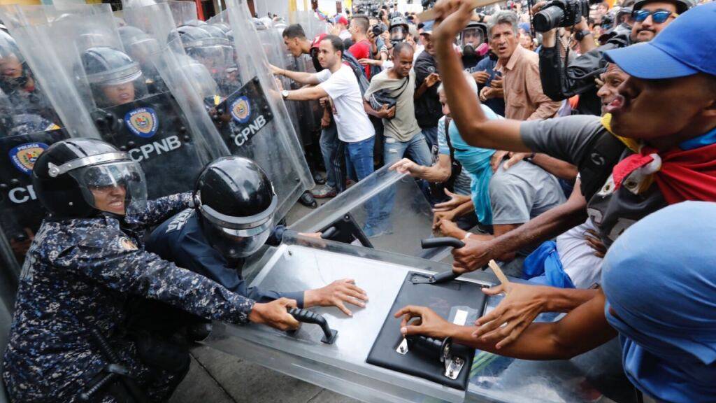 ARCHIV - Anhänger der Opposition ziehen an einem Schutzschild während eines Protests in Caracas (Archivbild). Foto: Ariana Cubillos/AP/dpa