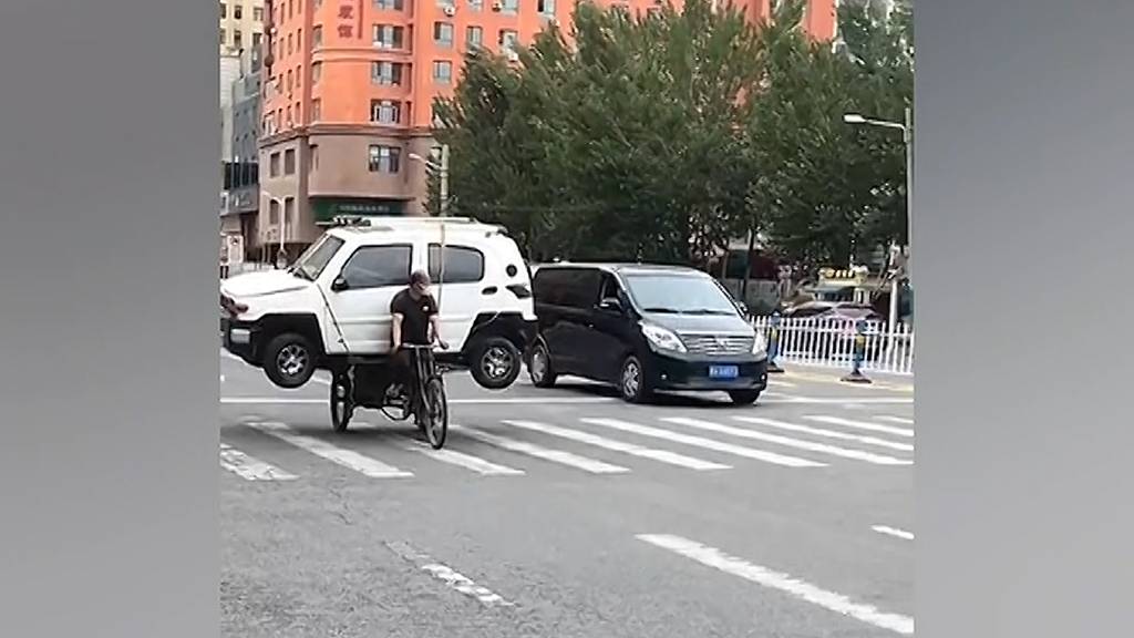 Mann transportiert Auto auf Dreirad-Gepäckträger