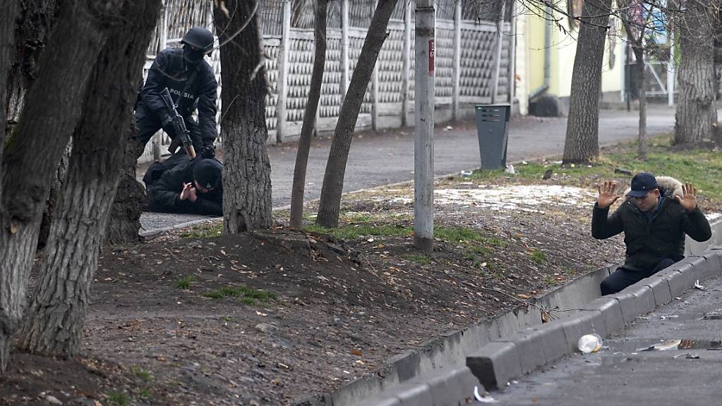 dpatopbilder - Ein bewaffneter Bereitschaftspolizist hält zwei Demonstranten während einer sogenannten Anti-Terror-Operation in einer Straße in Almaty, Kasachstan, fest. Foto: Vasily Krestyaninov/AP/dpa