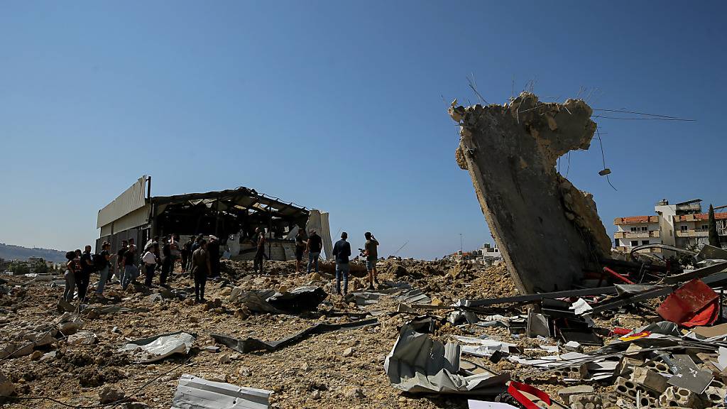 Menschen begutachten die Schäden, die durch einen nächtlichen israelischen Luftangriff in der Gegend von Jiyeh an der Küstenstraße zwischen der südlichen Hafenstadt Sidon und Beirut entstanden sind. Foto: Marwan Naamani/dpa