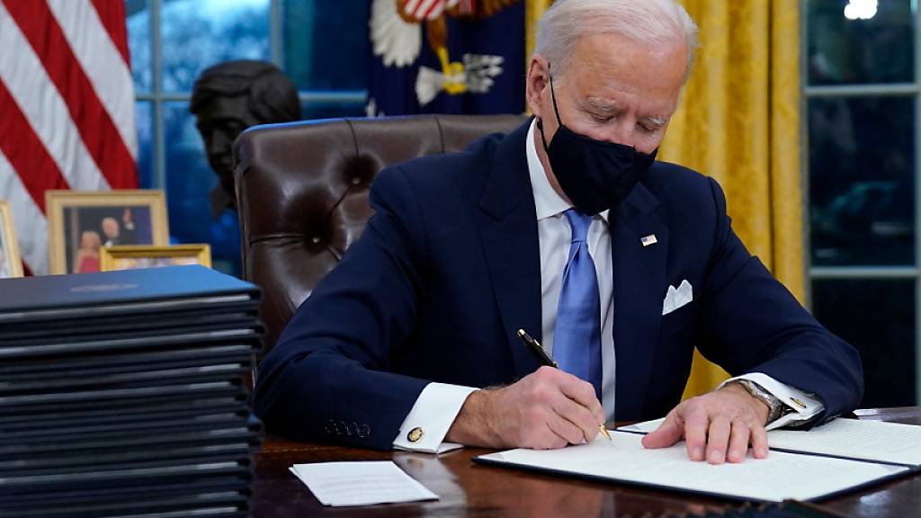 US-Präsident Joe Biden unterzeichnet seine erste Anordnung (Executive Order) im Oval Office des Weißen Hauses. Foto: Evan Vucci/AP/dpa