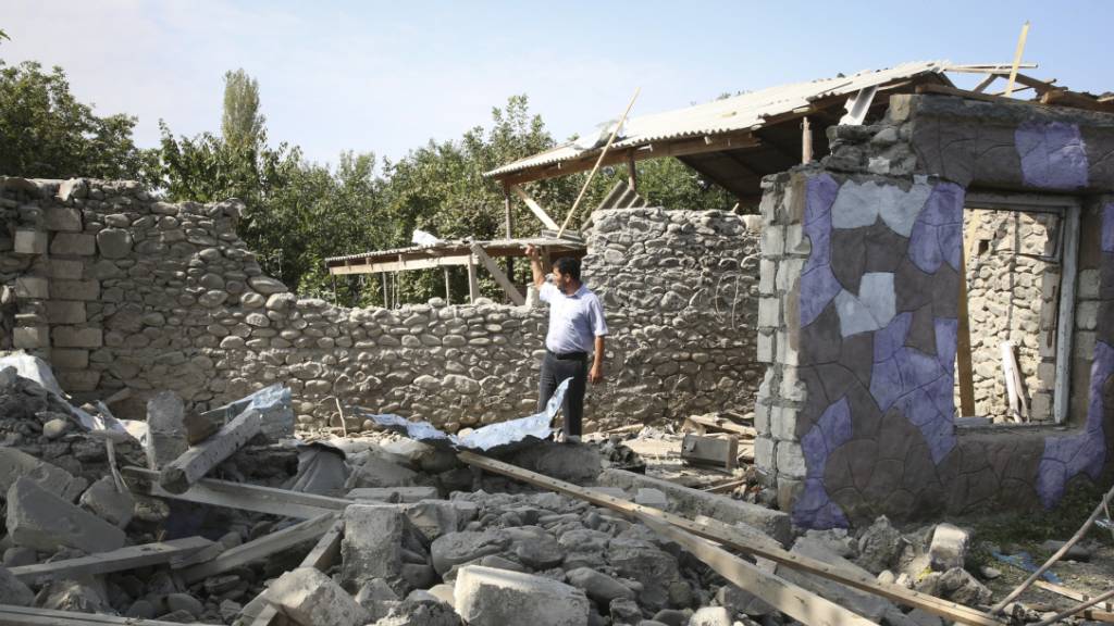 Ein Mann steht in den Ruinen eines Hauses, das angeblich während der Kämpfe beschädigt wurde.