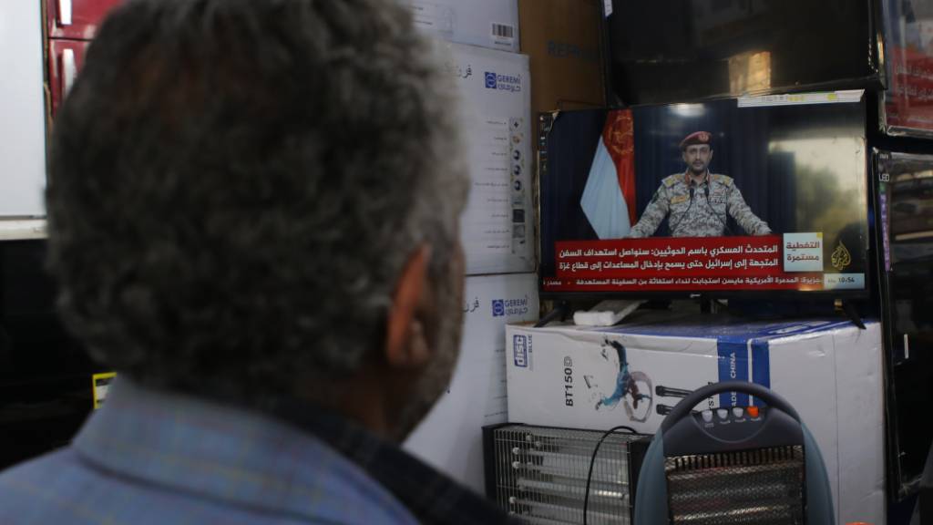 Jemeniten sehen eine im Fernsehen übertragene Erklärung von Yahya Saree, Sprecher der Houthi-Rebellen, an. In einer offenbaren Ausweitung ihrer Attacken auf Schiffe im Roten Meer haben die Huthi-Rebellen vor der Küste des Jemens einen Tanker direkt angegriffen. Foto: Osamah Yahya/ZUMA Press Wire/dpa