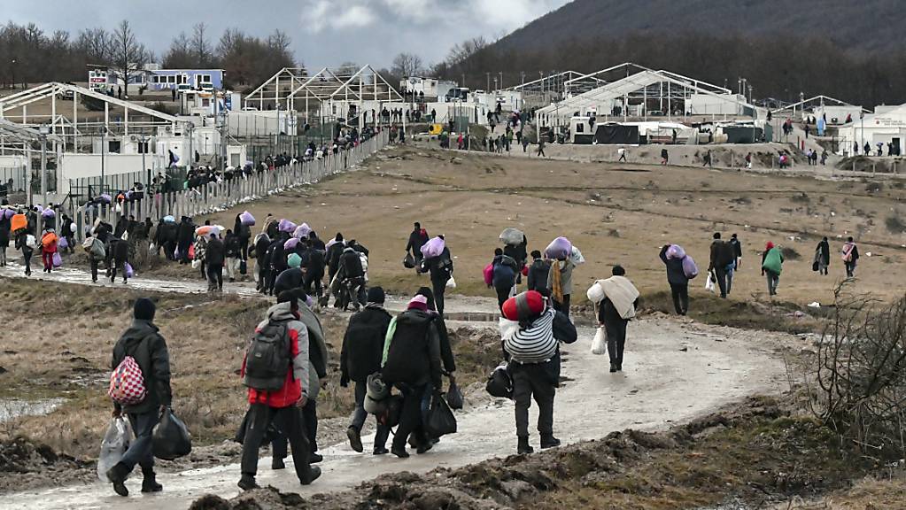 Migranten gehen am 30. Dezember 2020 mit ihren Habseligkeiten zurück zum Lager Lipa. Foto: Kemal Softic/AP/dpa